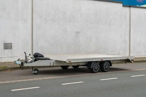 Car trailer platform standing on the side of the road along a concrete fence. Stock Photos
