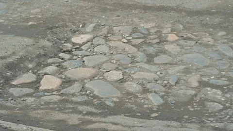 A car travels over a bumpy road with uneven stones and potholes, causing the Vidéo 344675586