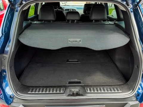 A car trunk is open and empty, showing its spacious interior. The ground is f Stock Photos