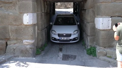 Car is trying to pass through the narrow and low stone tunnel Stock Footage 157123574