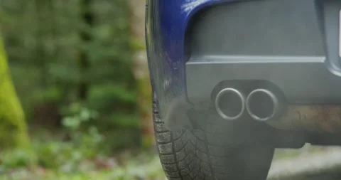 Car twin exhaust pipe tips emitting smoke or condensation while revving Stock Footage 323442021