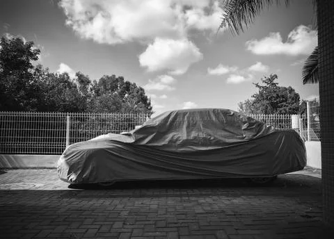 Car under a protective cover parked on the street Stock Photos