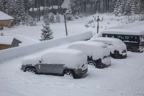 Car under a thick layer of snow. Snow-covered cars during a winter blizzard Stock Photos