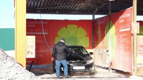 Car wash activity at an automatic wash station in winter near a busy highway Stock Footage 328438145