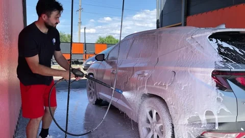 Car wash. Cleaning the car using high pressure water spraying. White soap foam. Stock Footage 245451789
