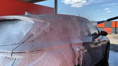 Car wash. Cleaning the car using high pressure water spraying. White soap foam. Stock Footage 245479070