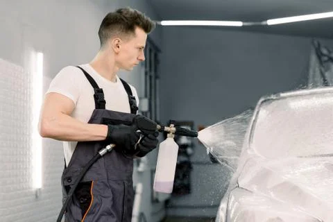Car wash with flowing water and foam. Side view of young car wash service male Stock Photos