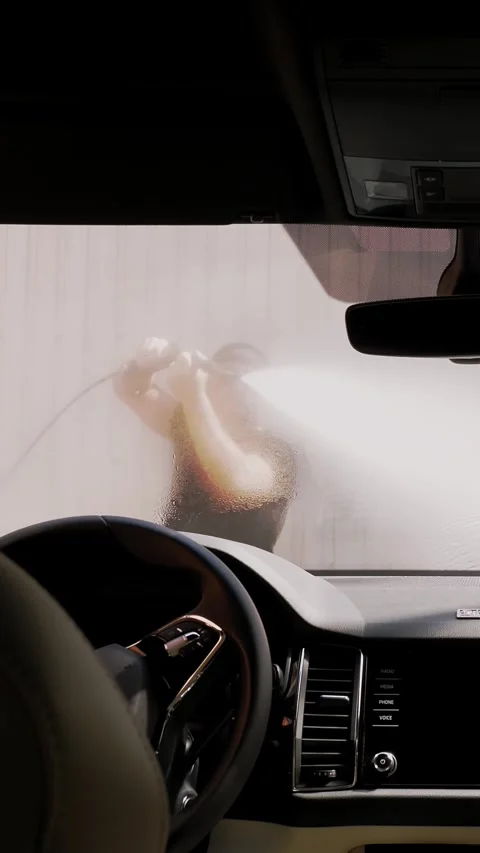 Car wash. A man washes a car with clean water high pressure spray, outside, at Stock Footage 314890329