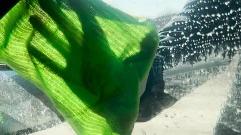 Car wash session captured, lathered-up windshield, hand applying cleansing foam Stock Footage 308822449