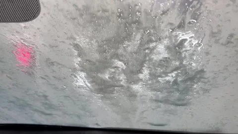 Car wash soap suds running down a windshield from inside view Stock Footage 340527341