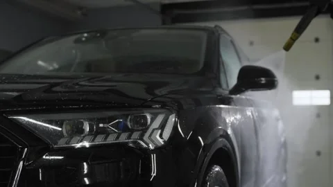 A car wash worker washes the driver's door of a black car. Stock Footage 244008696