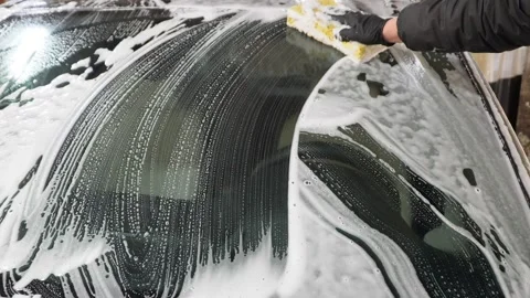 Car washer does full body car wash with soap and yellow sponge. Stock Footage 331529383