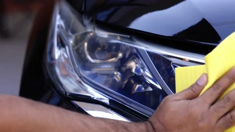 The car washer uses a yellow sponge soaked with varnish to scrub it onto the hea Stock Footage 152747892