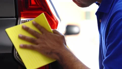 Car washers use a sponge to wipe the car tail lights with cleaning solution to k Stock Footage 152747886