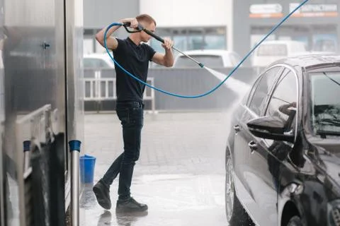 Car washing. Cleaning car using high pressure water. Man washing his car outdoor Stock Photos