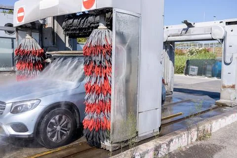 Car washing process in Automatic Car washer. Water spraying, rinsing dirt and Stock Photos