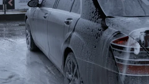 Car washing process of luxury car full covered with white foam and splashes from Stock Footage 144697828