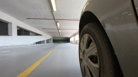 Car wheel driving inside a modern indoor parking garage, low angle action shot Vidéo 333560976