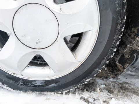 Car wheel on slow covered surface at winter day, flat cast silver disc Stock Photos
