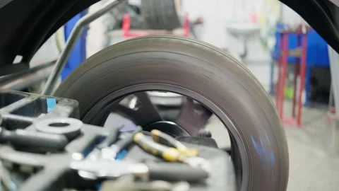 Car wheel spinning on a balancing machine in a professional auto service Stock Footage 339273797