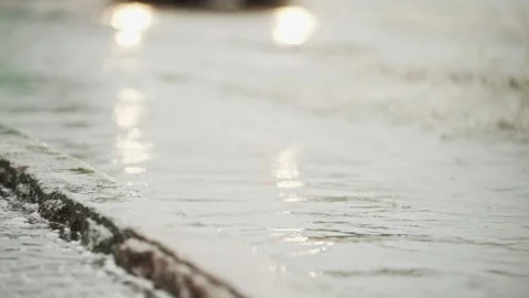 Car Wheel Splashing Through Puddle on Rainy City Street Close Up Stock Footage 340483224