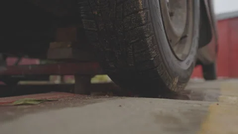 Car wheel with tire close up installed on repair pit is lifted with jack for Stock Footage 263657403