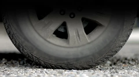 Car wheel turning and trying to gain traction against the gravel road surface Stock Footage