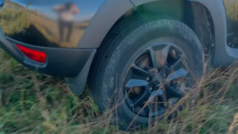 Car wheels moving backward on grassy terrain, vehicle reversing across uneven Stock Footage 333617150