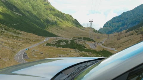 A car on a winding mountain road surrounded by lush green mountains and valleys Stock Footage 308574048