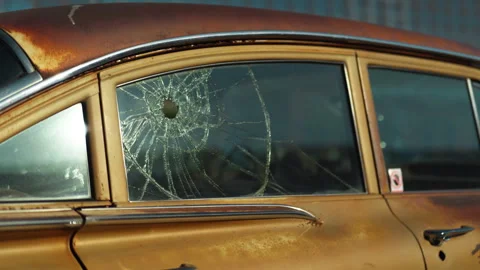 Car window shattered by multiple bullet holes on a city Stock Footage 330954336