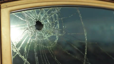 Car window shattered by multiple bullet holes on a city Stock Footage 330954476