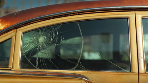 Car window shattered by multiple bullet holes on a city Stock Footage 330954492