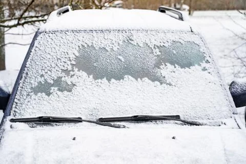 Car window under a layer of snow. Snow cover texture on smooth glass car 写真素材