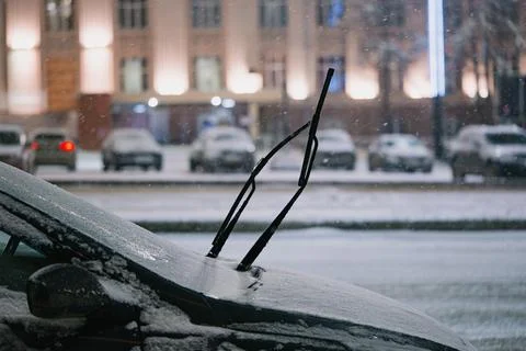 Car windshield and wipers covered in fresh snow during a cold winter evening Stock Photos