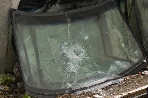 Car windshield with shattered impact point creates dramatic damage scene. Stock Photos