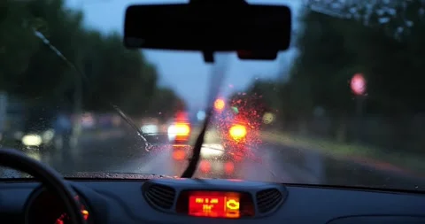 Car windshield view during rainy dusk drive with wipers clearing water drops Stock Footage 340385476
