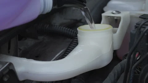 Car windshield washer fluid pouring into plastic reservoir in engine bay with Stock-Footage 323413249