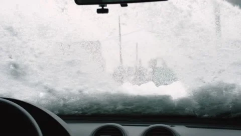 Car wipers clean the windshield of snow from inside the car in winter. Cold Stock Footage 222920932