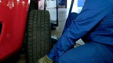 Car worker puts on a car wheel Stock Footage 71199941