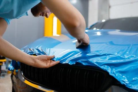 Car wrapper puts protective foil or film on hood Stock Photos