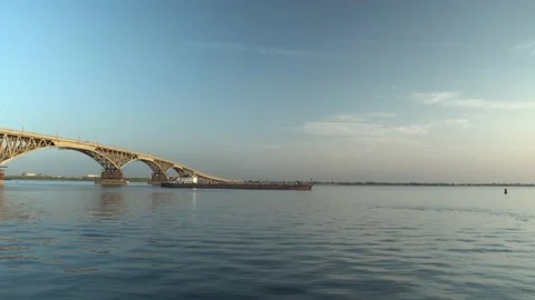 Carable passes under a bridge in the setting sun along a calm river Video stock 148103919