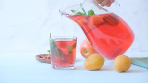 Carafe of fruit compote. A woman's hand pours compote into a glass. Stock Footage 279972524