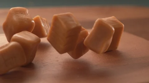 Caramel candy falling onto wooden surface in super slow motion.  Shot on Phantom Stock Footage 117517860