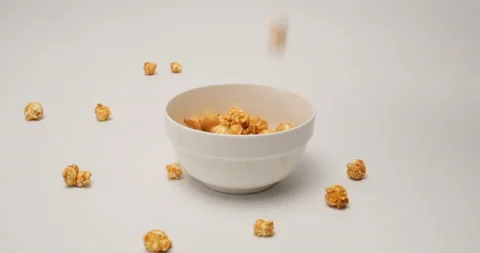 Caramelized popcorn falling into a whiite cup, ready to eat Stock Footage 154409744