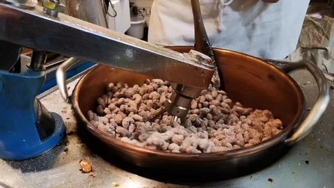 Caramelizing peanuts,almonds in brazier,hands sprinkling sugar in street stall Stock Footage 117678011