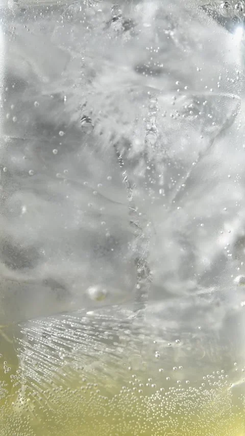 Carbonation bubbles rise around ice in sparkling apple cider and tonic drink, Stock Footage 345487159