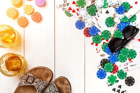 Card deck surrounded by poker chips and scattered seashells on white wooden Stock Photos