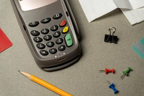 A card reader is on a gray table. Next to it are a pencil, colorful push pi.. Stock Photos