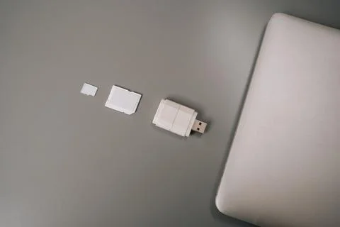 Card reader with micro sd card lying on gray table next to white laptop 库存照片