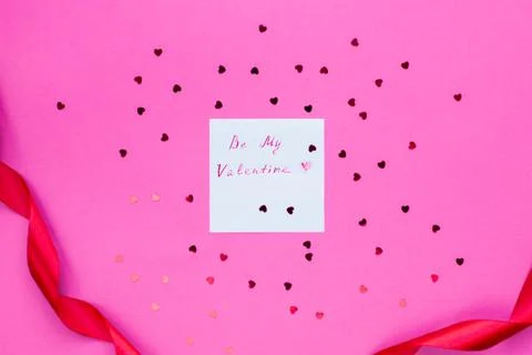 Card Will you be my valentine on pink background surrounded by hearts and a red Stock Photos